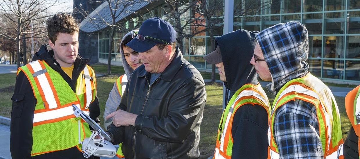 Civil engineering students and their professor working with a drone